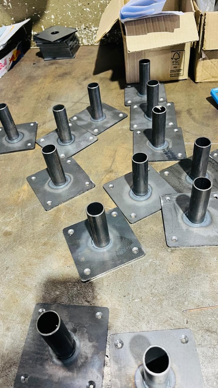 Welded tubes on square mounting plates arranged on a workshop bench