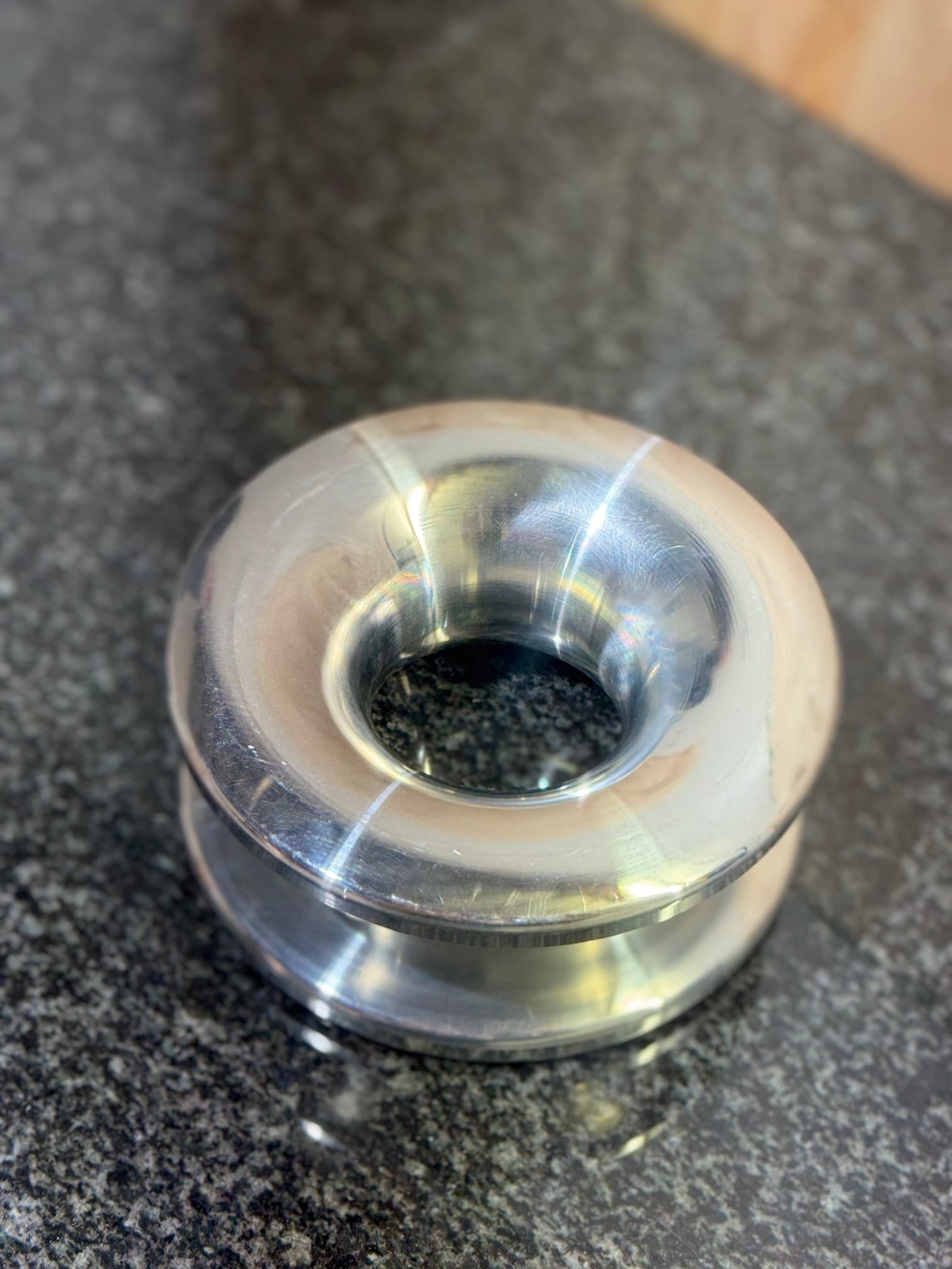 Circular machined component with a flared central opening, viewed from above